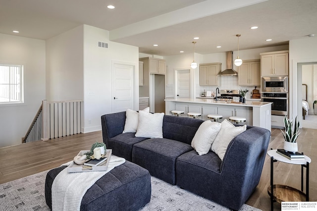 living area with light wood-style flooring, recessed lighting, visible vents, and baseboards