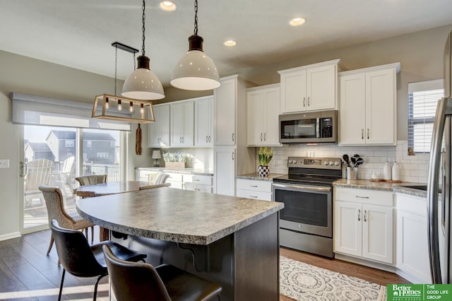 kitchen featuring a breakfast bar area, stainless steel appliances, white cabinetry, backsplash, and a center island