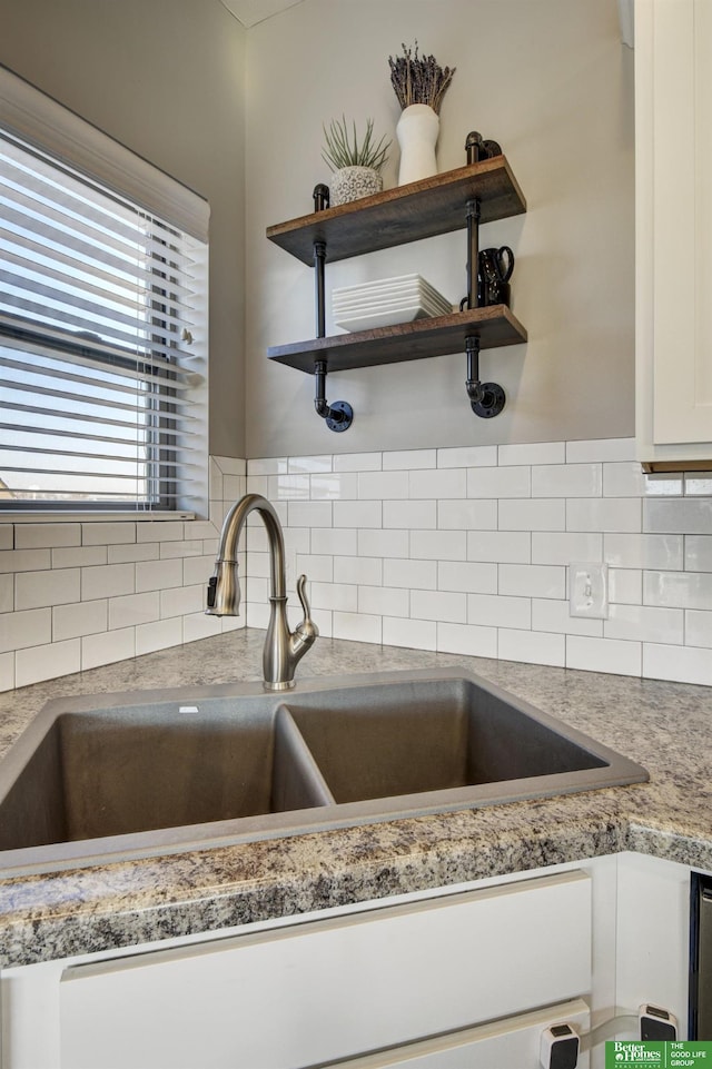 kitchen featuring open shelves, a sink, decorative backsplash, light countertops, and white cabinetry