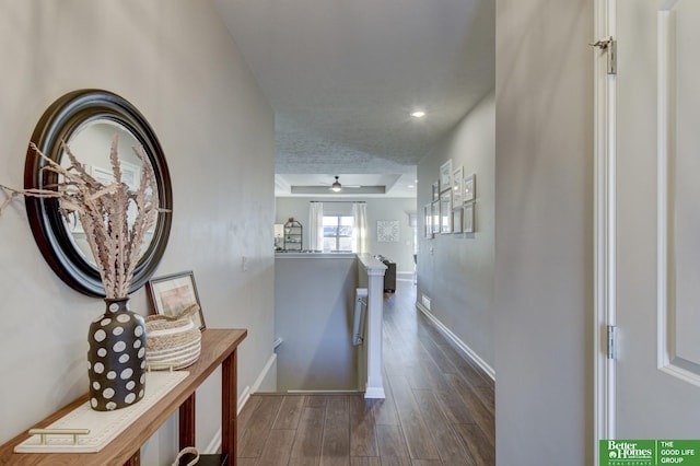 hall featuring baseboards, an upstairs landing, recessed lighting, a raised ceiling, and dark wood-style flooring