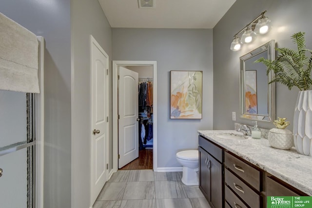 full bathroom with vanity, baseboards, visible vents, a spacious closet, and toilet