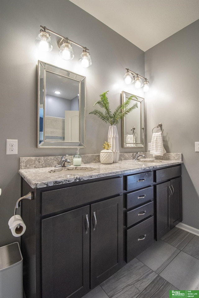 bathroom featuring double vanity, baseboards, and a sink