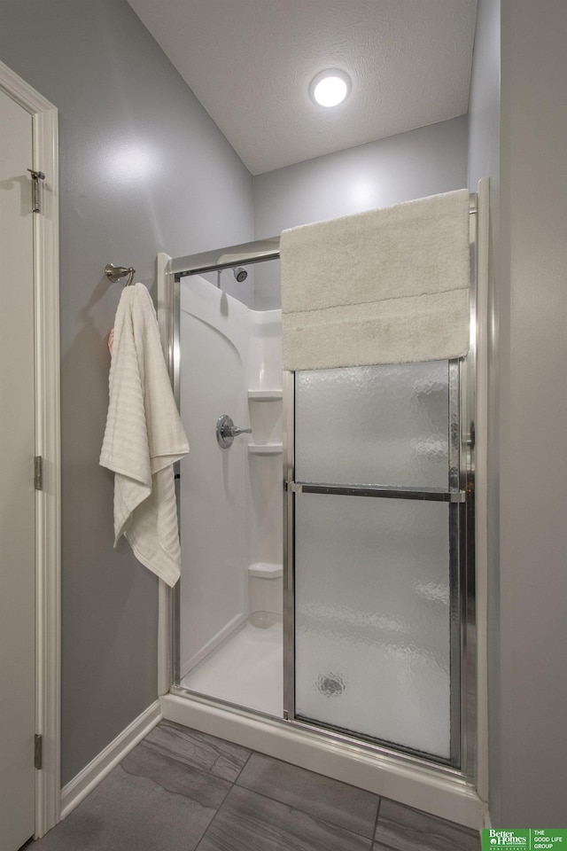 full bathroom with baseboards, a stall shower, and a textured ceiling