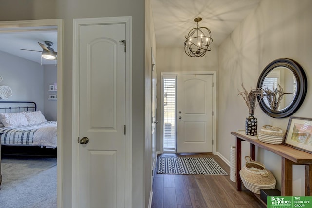 foyer entrance with baseboards, dark wood-type flooring, and a chandelier