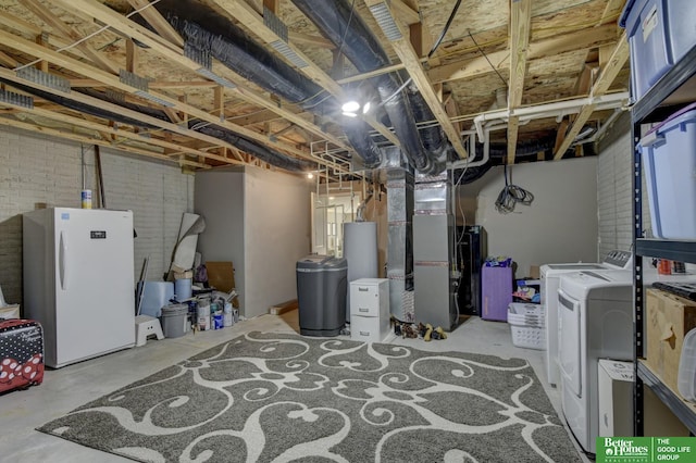 unfinished basement with heating unit, brick wall, washing machine and clothes dryer, freestanding refrigerator, and gas water heater