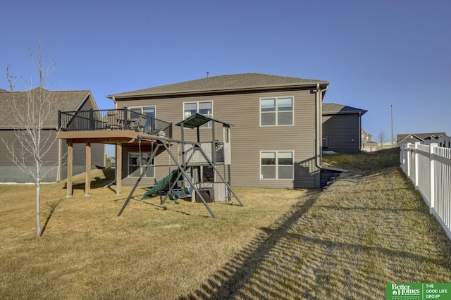 back of house featuring a deck, a playground, fence, and a lawn