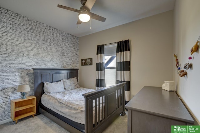 bedroom with light colored carpet, an accent wall, and a ceiling fan