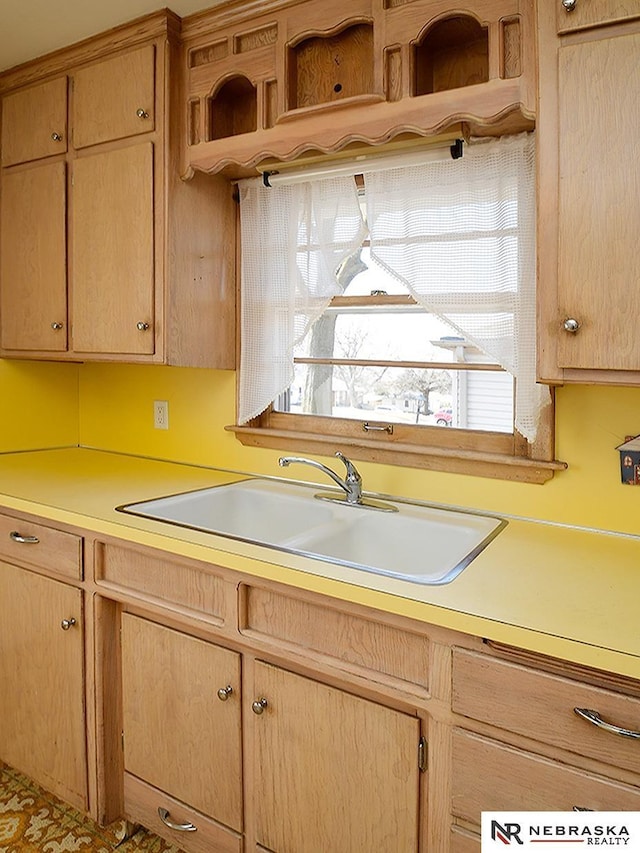 kitchen with light countertops, light brown cabinets, open shelves, and a sink