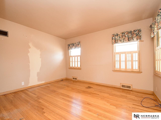 spare room featuring hardwood / wood-style flooring, baseboards, and visible vents