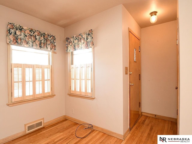 interior space featuring baseboards, visible vents, and light wood-type flooring