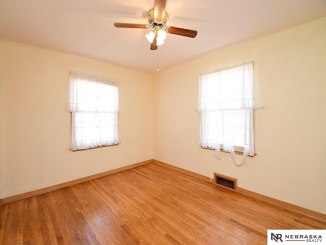 empty room featuring light wood finished floors, visible vents, baseboards, and ceiling fan