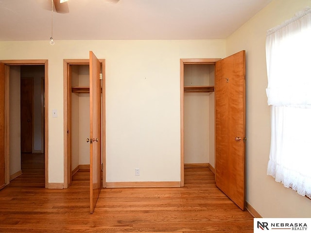 unfurnished bedroom featuring light wood-type flooring, multiple windows, and baseboards