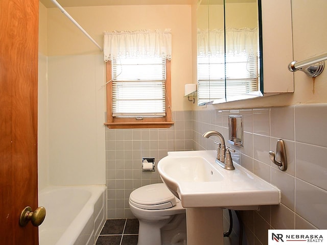 bathroom with tile patterned flooring, shower / washtub combination, toilet, and tile walls