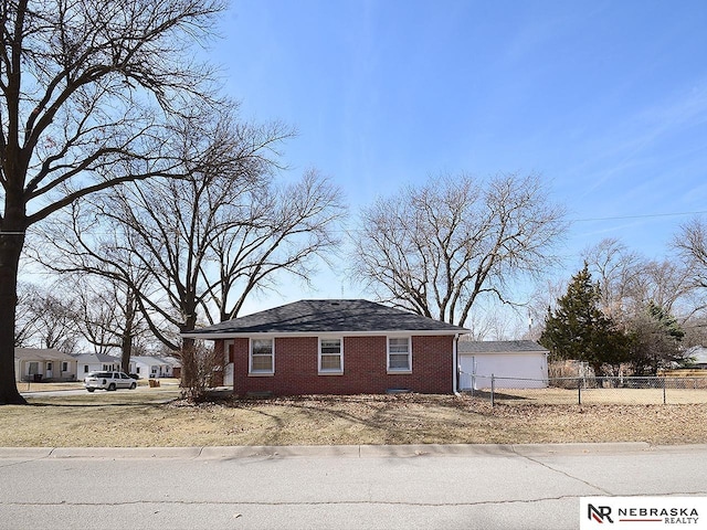 view of side of home with a garage, fence, and brick siding