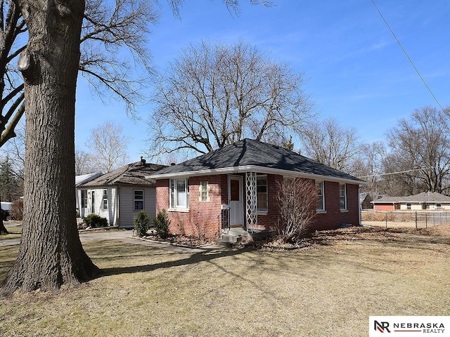 single story home with brick siding, a front lawn, and fence