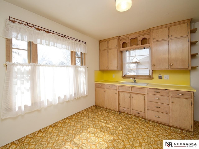 kitchen with light brown cabinets, a sink, open shelves, light countertops, and light floors