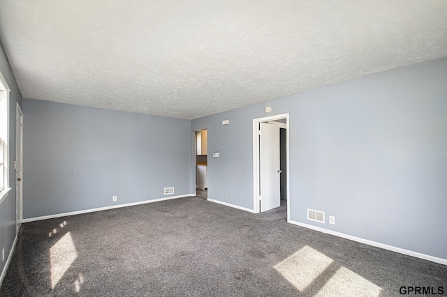 empty room featuring carpet flooring, baseboards, visible vents, and a textured ceiling