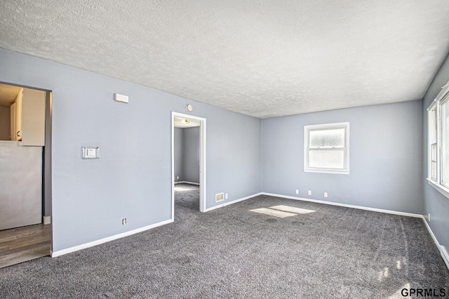 unfurnished bedroom featuring a textured ceiling, baseboards, carpet, and freestanding refrigerator