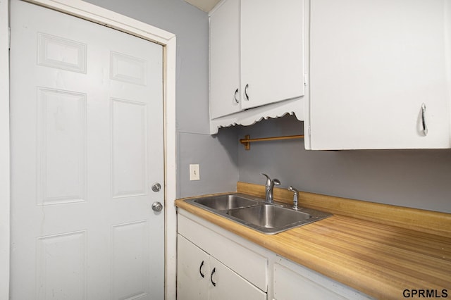 kitchen with white cabinetry, light countertops, and a sink