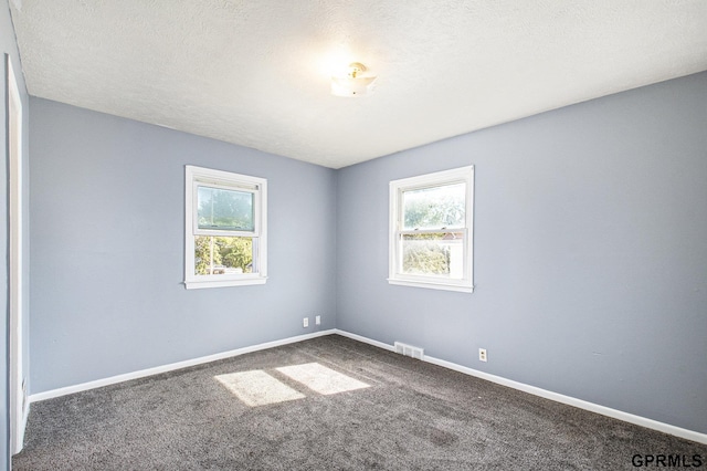 unfurnished room featuring carpet flooring, visible vents, a textured ceiling, and baseboards