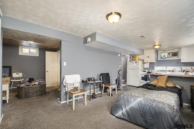 carpeted bedroom featuring a textured ceiling, freestanding refrigerator, baseboards, and a sink