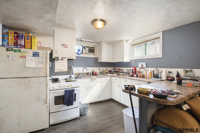 kitchen with a peninsula, dark wood-style floors, white appliances, white cabinetry, and a sink