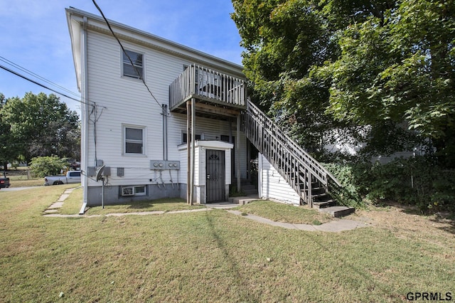 back of house featuring a lawn and stairs