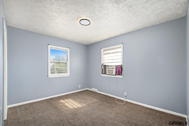 carpeted spare room featuring cooling unit, a textured ceiling, and baseboards