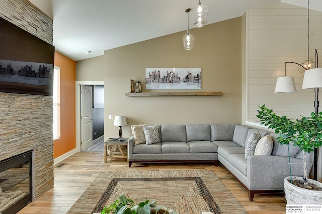 living area with a stone fireplace, wood finished floors, and high vaulted ceiling