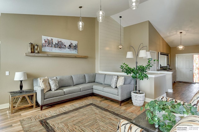 living area featuring high vaulted ceiling, baseboards, and wood finished floors