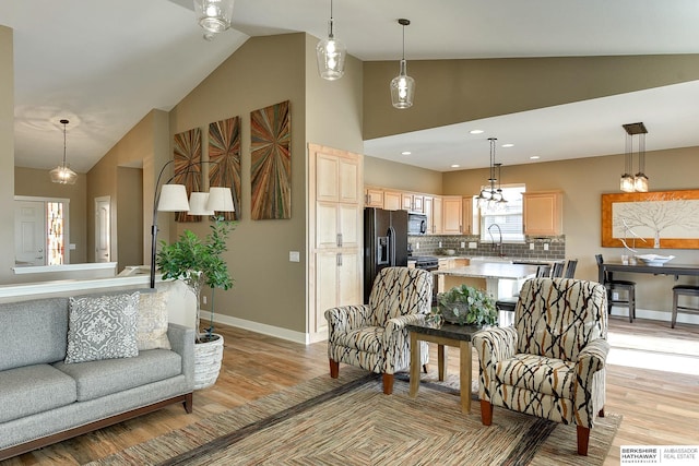 living room with high vaulted ceiling, recessed lighting, baseboards, and light wood-style floors