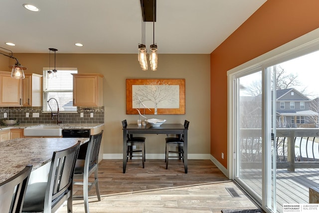 kitchen featuring visible vents, light wood-style flooring, light brown cabinets, a sink, and tasteful backsplash