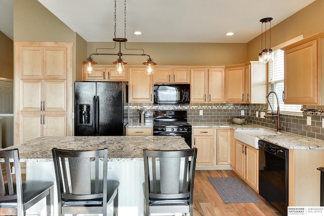 kitchen with tasteful backsplash, light brown cabinets, a breakfast bar, black appliances, and a sink