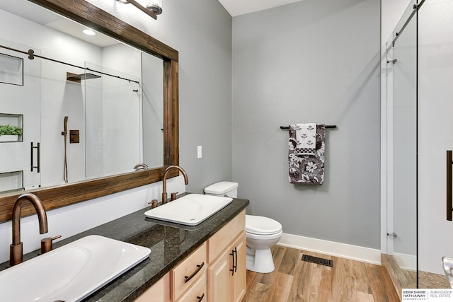 full bathroom with visible vents, a shower stall, wood finished floors, and a sink