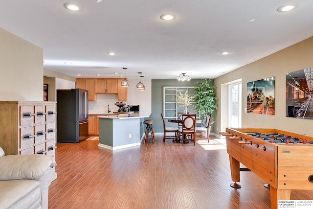 kitchen featuring pendant lighting, light countertops, a peninsula, high quality fridge, and light wood-style floors