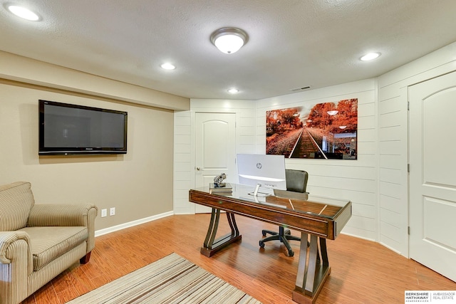 office area with light wood-style flooring, recessed lighting, visible vents, and a textured ceiling