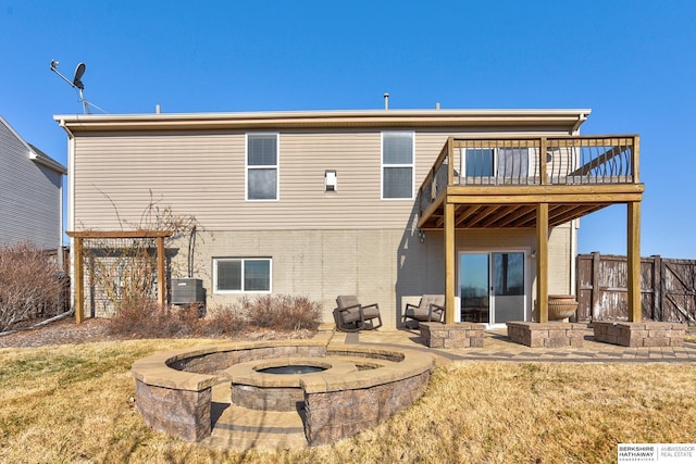 rear view of property with a wooden deck, fence, and a fire pit