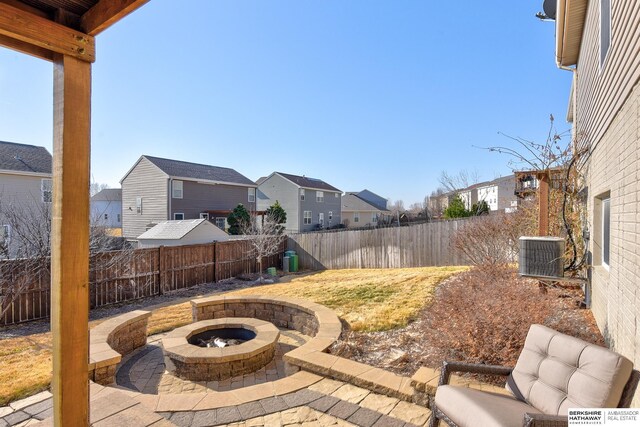 view of patio / terrace with cooling unit, a fenced backyard, a residential view, and an outdoor fire pit