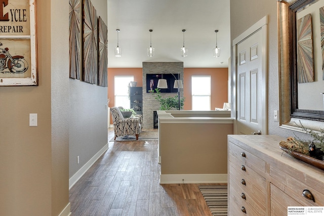 kitchen with hanging light fixtures, open floor plan, wood finished floors, and baseboards