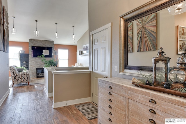 kitchen featuring a wealth of natural light, baseboards, wood finished floors, and a fireplace