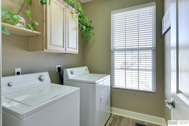 laundry area featuring wood finished floors, cabinet space, baseboards, and washer and clothes dryer