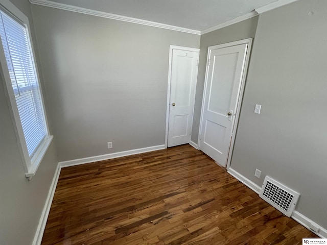 unfurnished room with dark wood finished floors, visible vents, baseboards, and ornamental molding