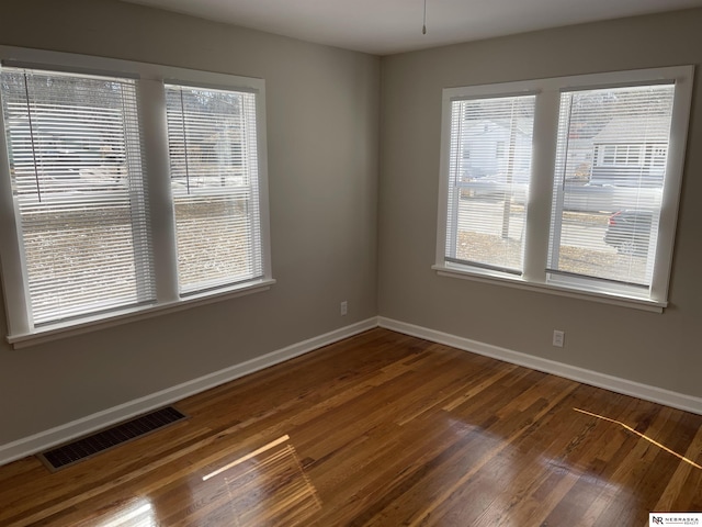 spare room with visible vents, baseboards, and wood finished floors