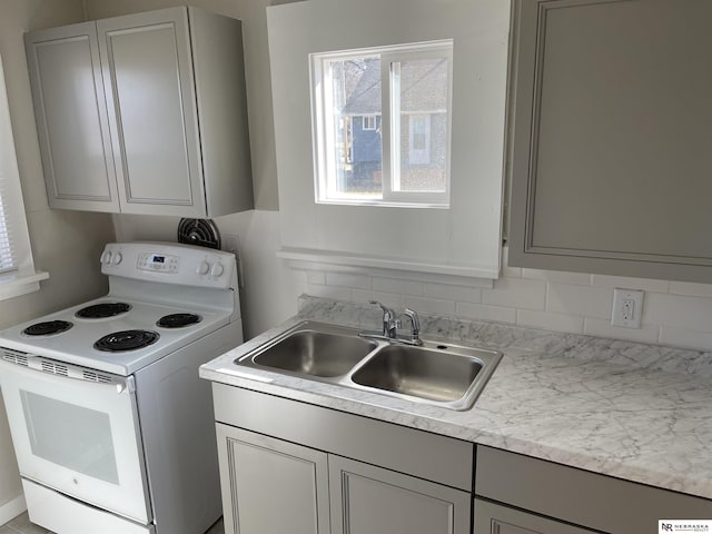 kitchen with a sink, gray cabinets, light countertops, and white electric range oven