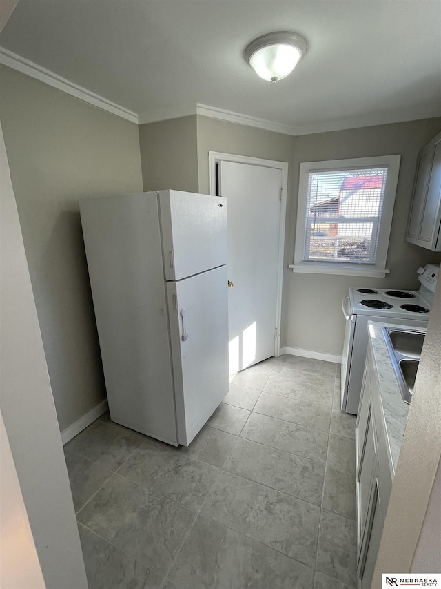 kitchen featuring a sink, white appliances, baseboards, and ornamental molding