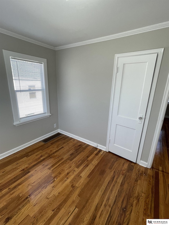 unfurnished room featuring dark wood-style flooring, baseboards, visible vents, and ornamental molding