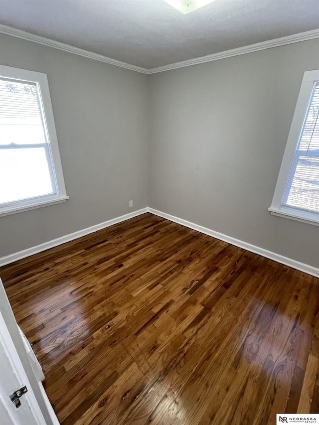 spare room featuring baseboards, dark wood-style flooring, and ornamental molding