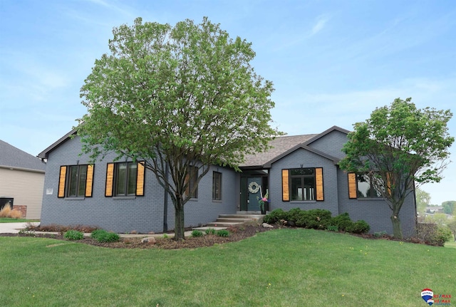 view of front of home featuring brick siding, roof with shingles, and a front lawn