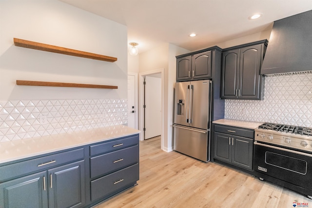 kitchen featuring open shelves, light countertops, light wood-style floors, wall chimney exhaust hood, and premium appliances