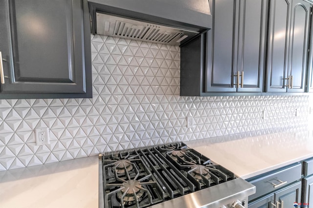 kitchen with gray cabinetry, decorative backsplash, light countertops, cooktop, and under cabinet range hood